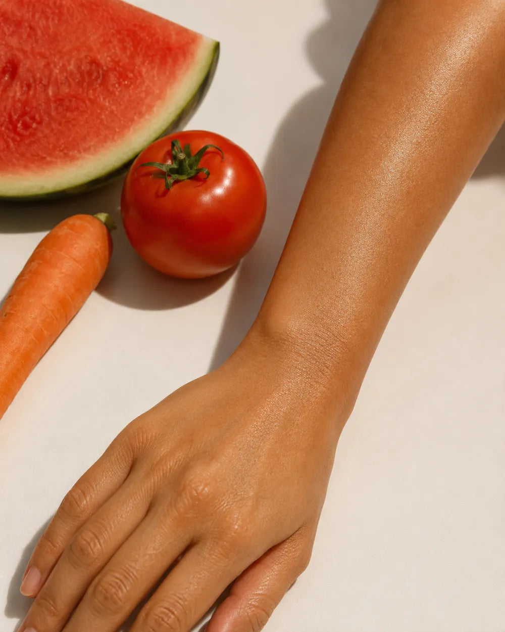An even golden-bronze arm beside carrot, tomato and watermelon — real color from real pigments